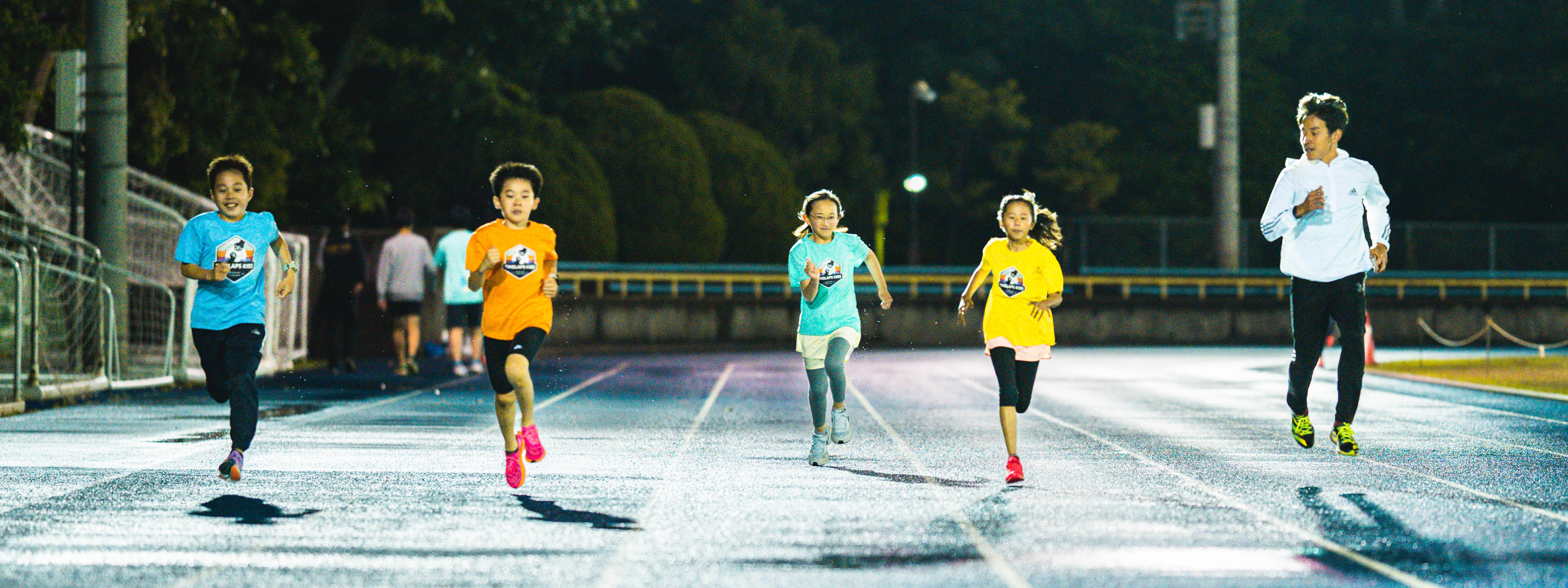走る子どもたちとコーチの写真